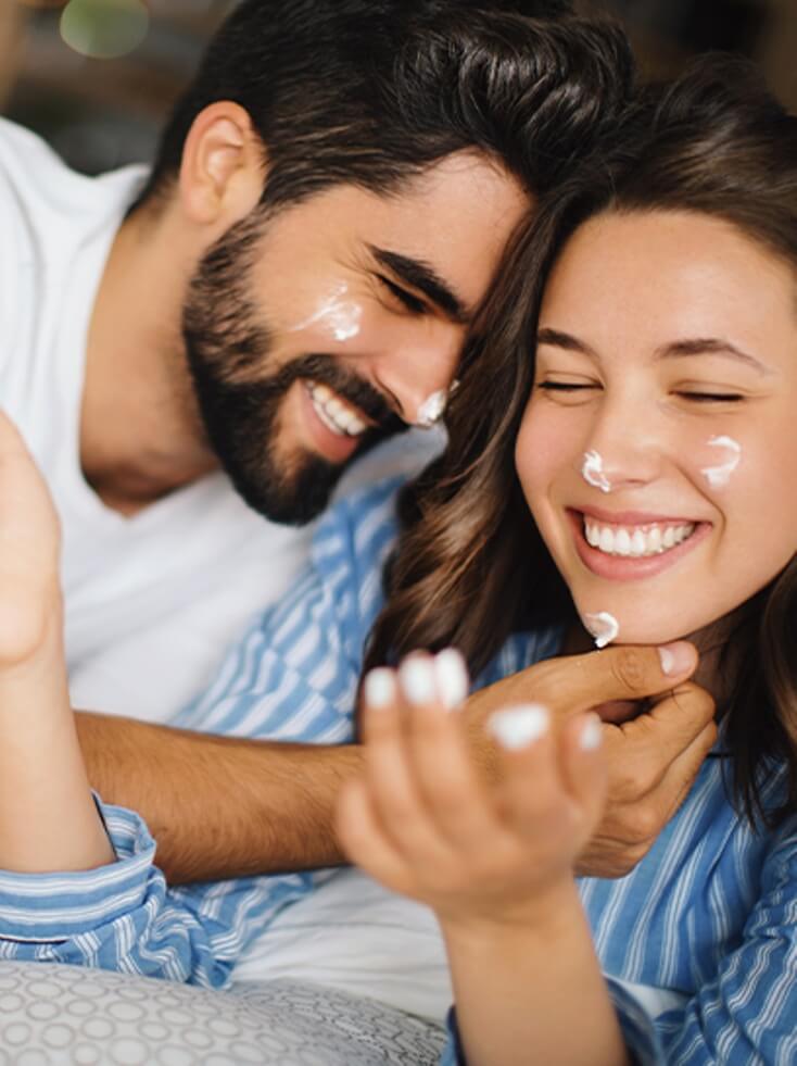 Couple applying Aloe Vera Cream with Propolis and smiling together.